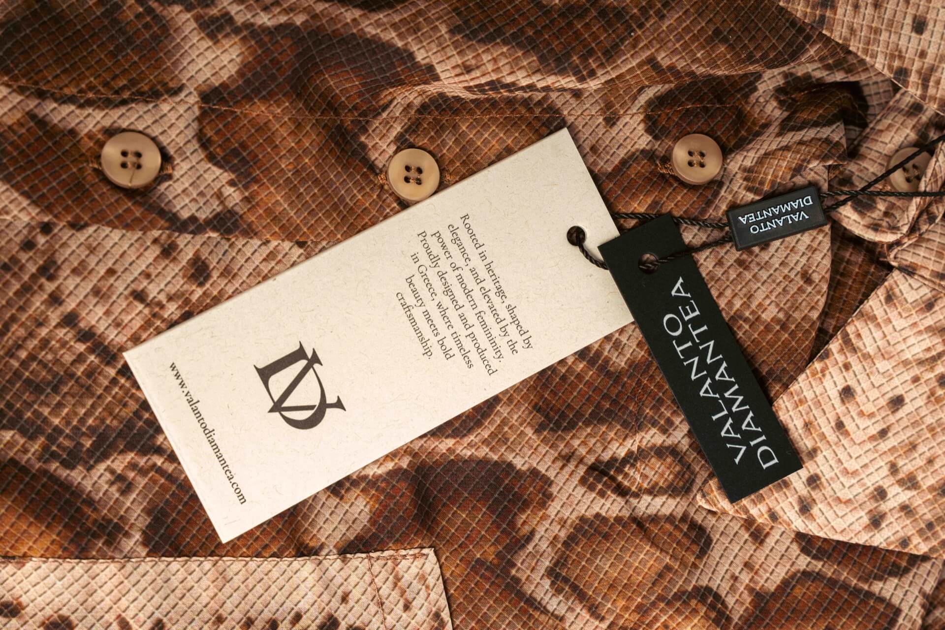 Close-up of a patterned fabric with a tag and button, featuring the brand 'Valanto Diamantea'.