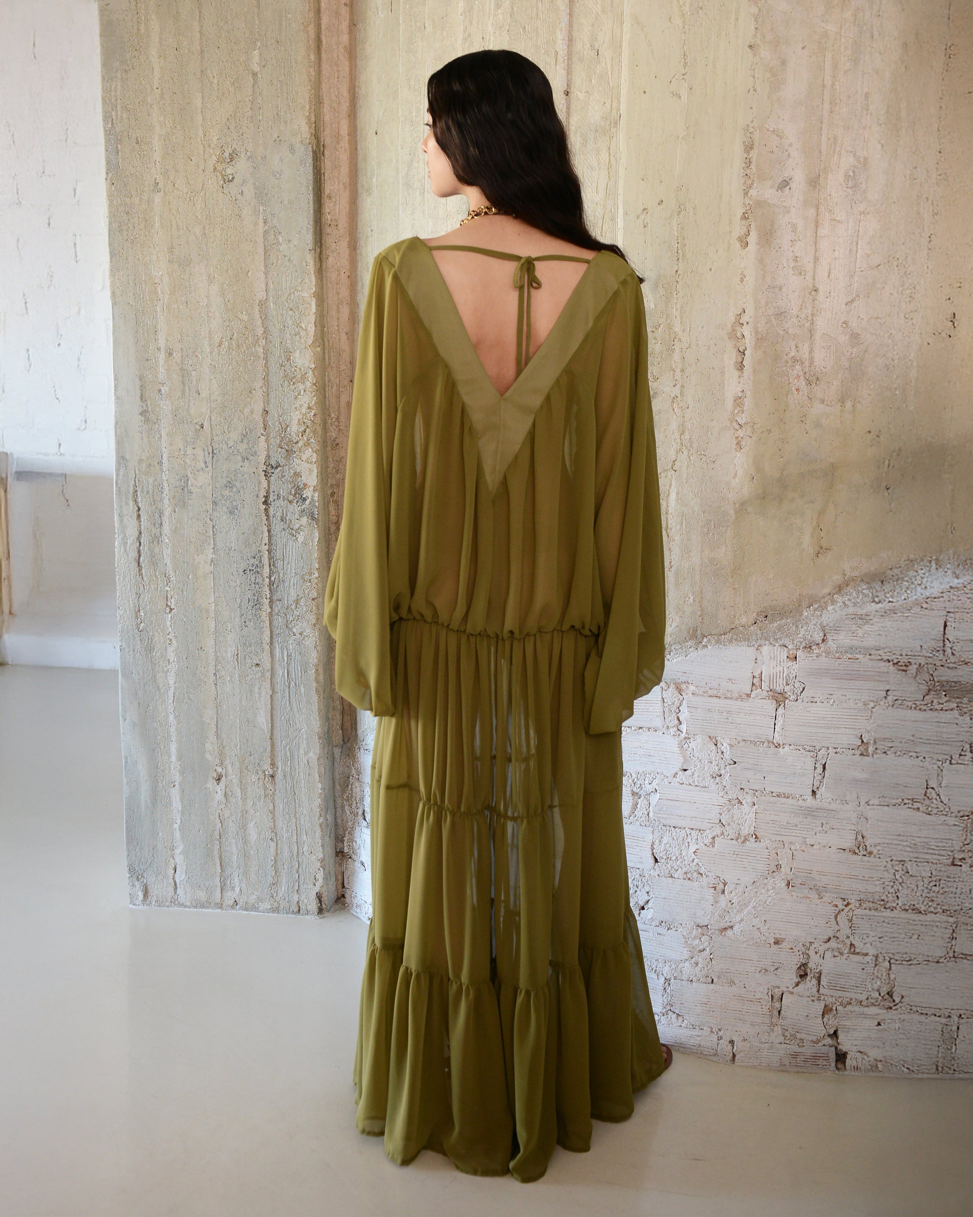 Woman wearing a green dress with a textured wall background