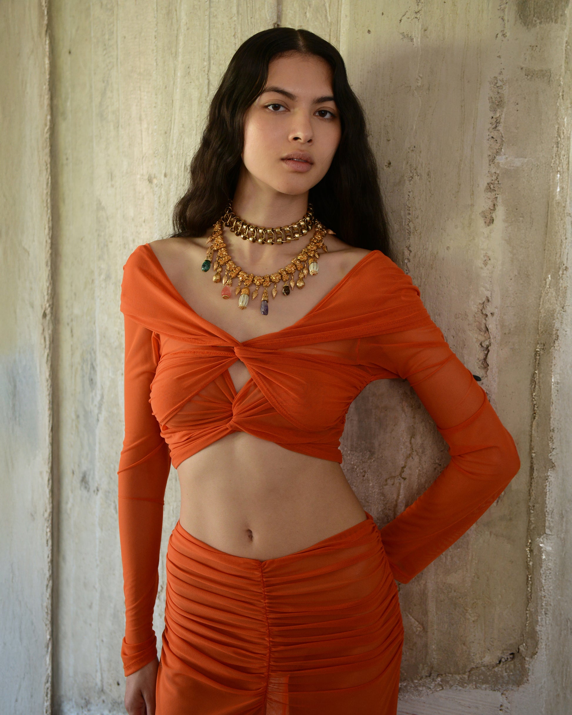 Woman wearing an orange outfit with a textured wall background
